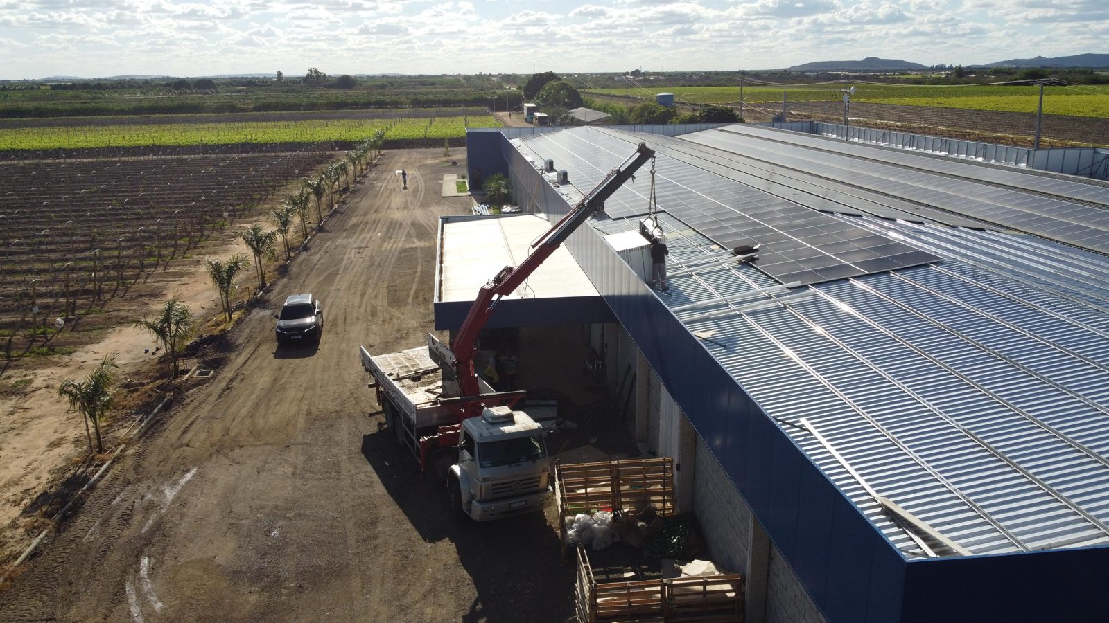 Usina solar sobre telhado industrial com módulos içados por guindauto