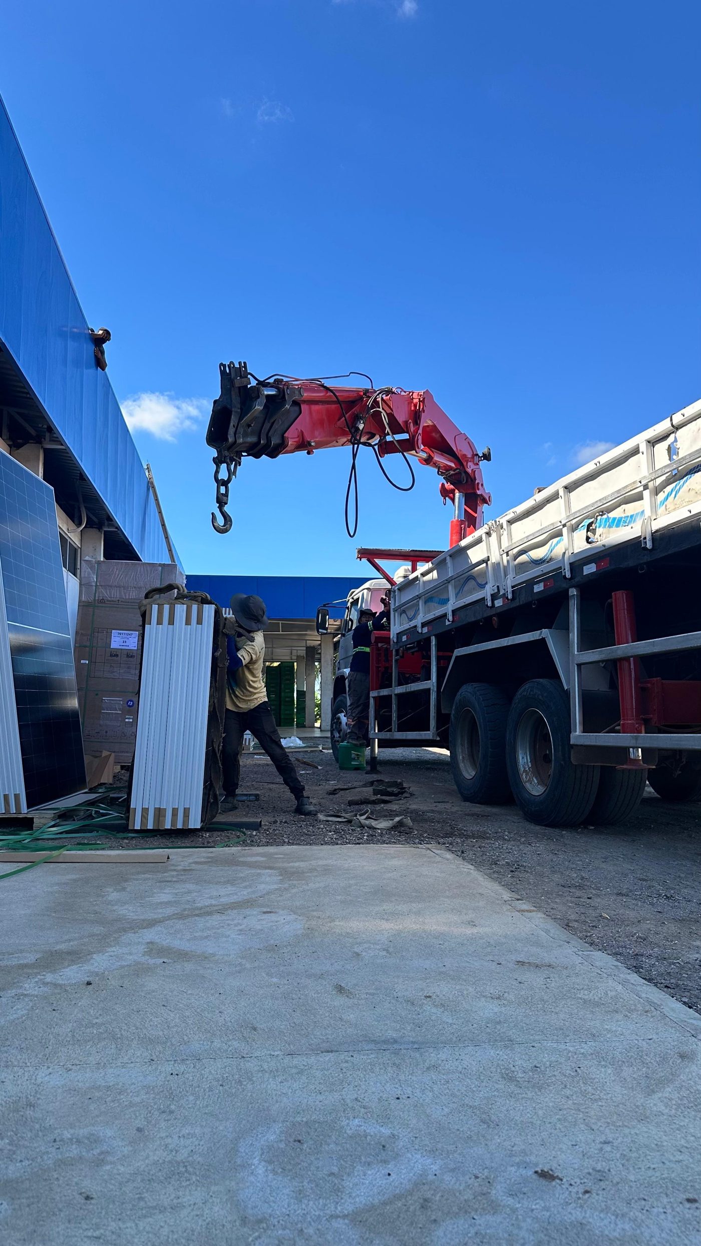 Guindauto içando módulos fotovoltaicos em obra